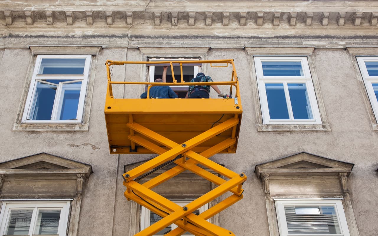 Schaarhoogwerker bij een woninggevel voor raamwerkzaamheden